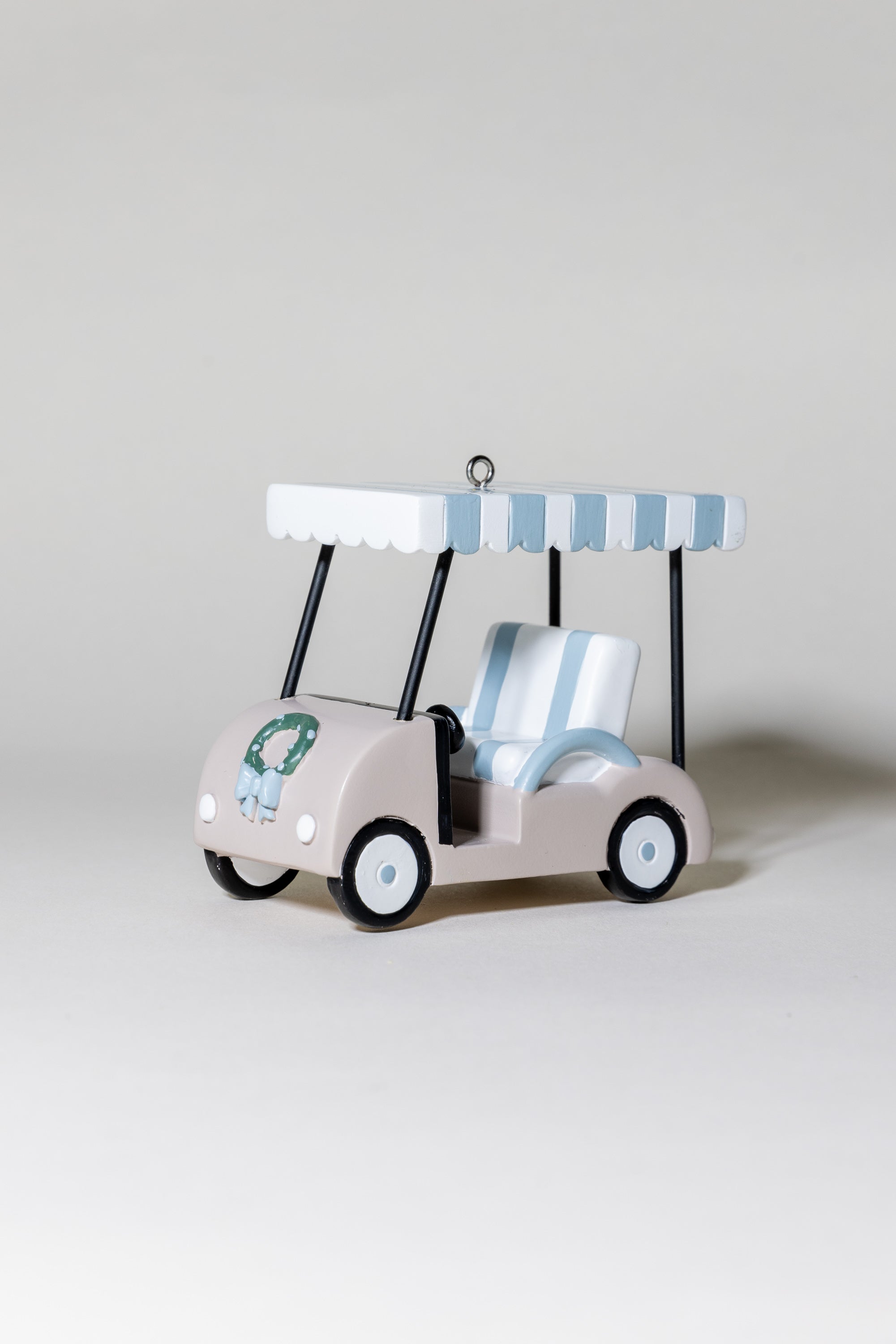 Toy golf cart with striped canopy on a light gray background