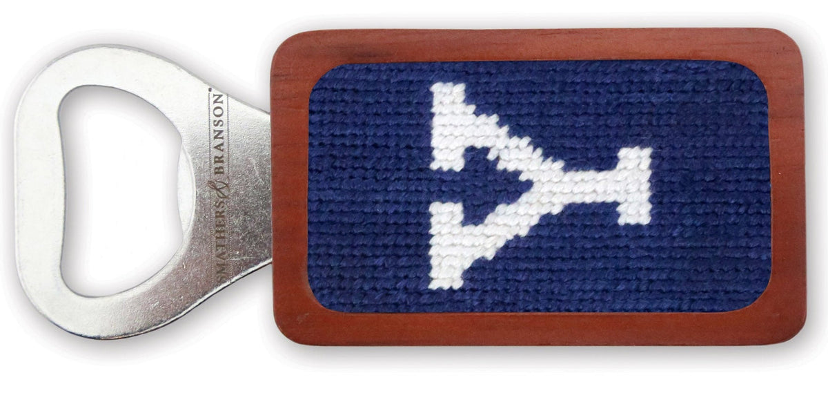 Rectangular bottle opener with a blue needlepoint design and white logo on a white background