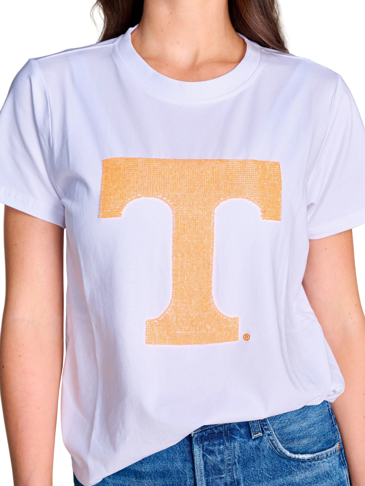 A white short-sleeve crewneck t-shirt featuring a large, textured orange block letter 'T' on the front, worn by a model with blue jeans against a light beige background. Tennesse Women's t-shirt