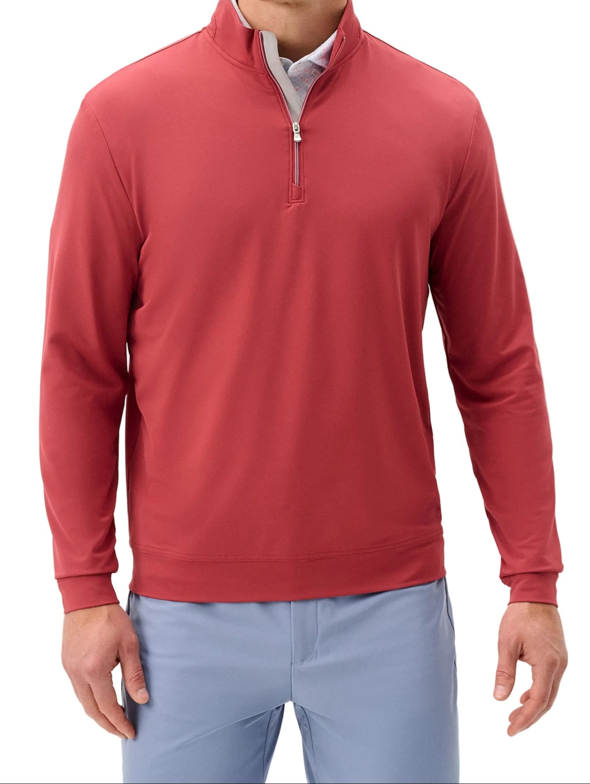 Man wearing a red quarter-zip pullover and light blue pants on a white background