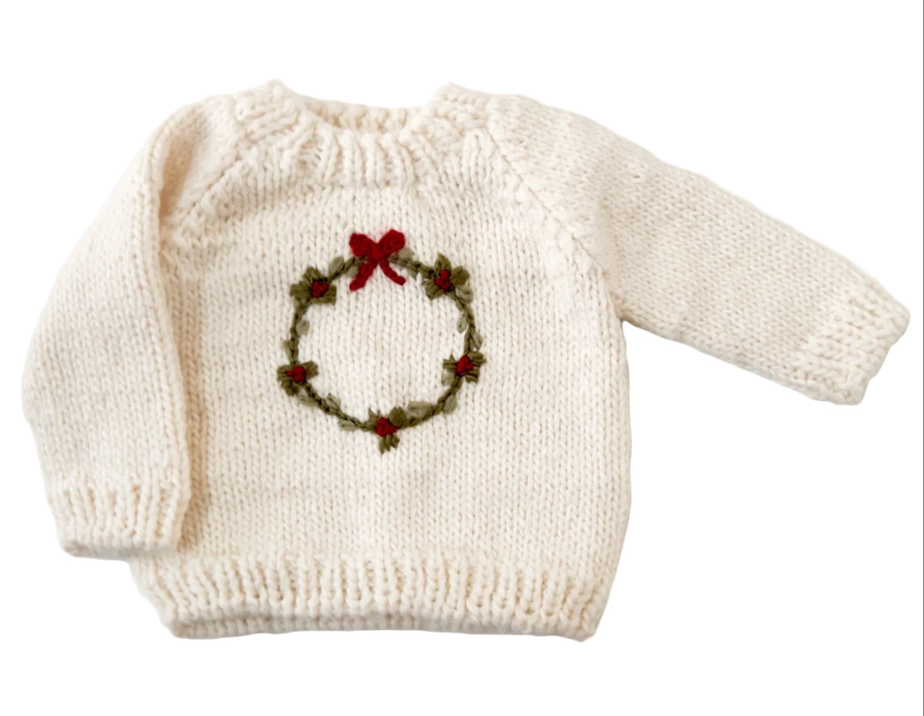 White sweater with a Christmas wreath design on a white background