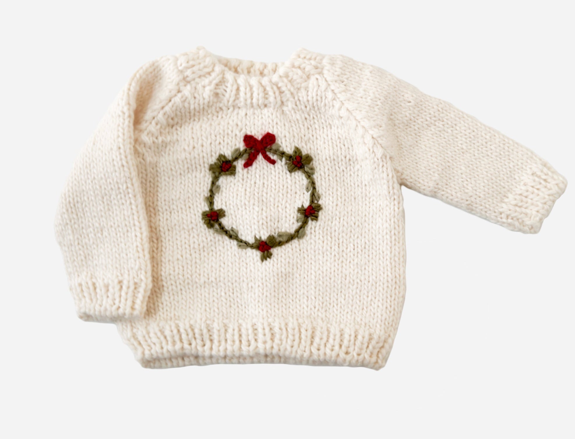 White sweater with a Christmas wreath design on a white background