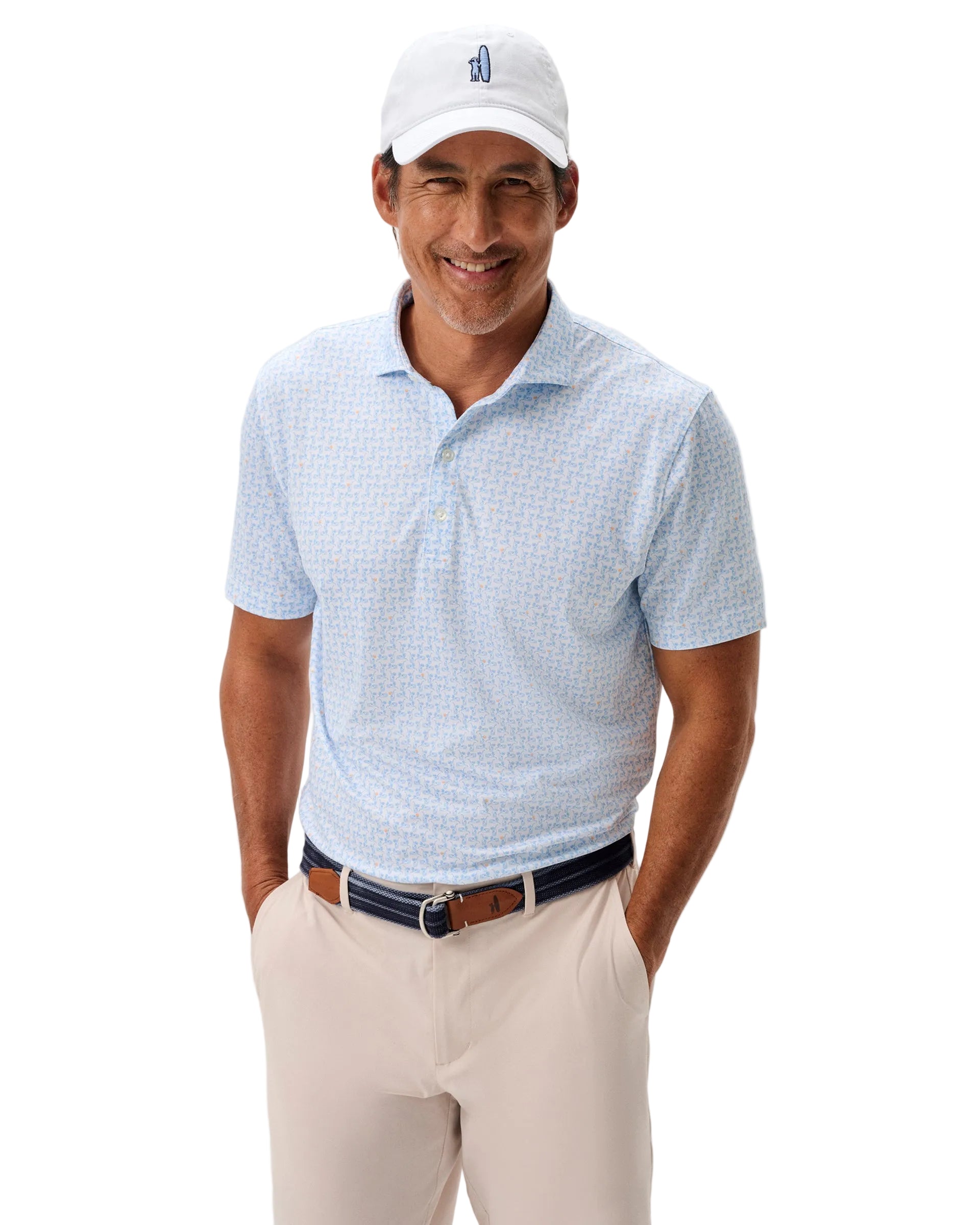 Man wearing a light blue checkered polo shirt, beige pants, and a white cap with a logo on a plain background