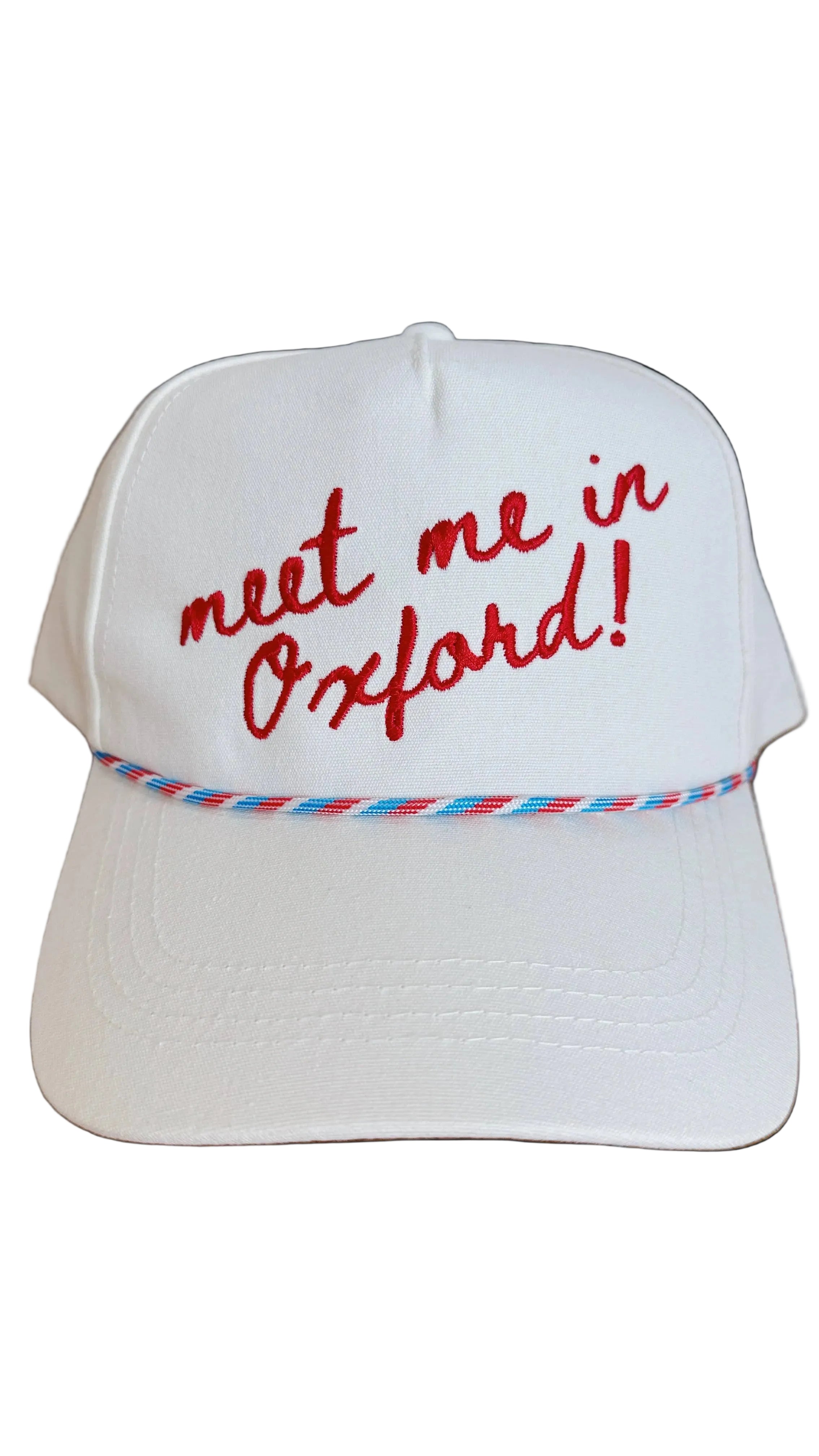 White cap with 'meet me in Oxford!' text on a wooden surface