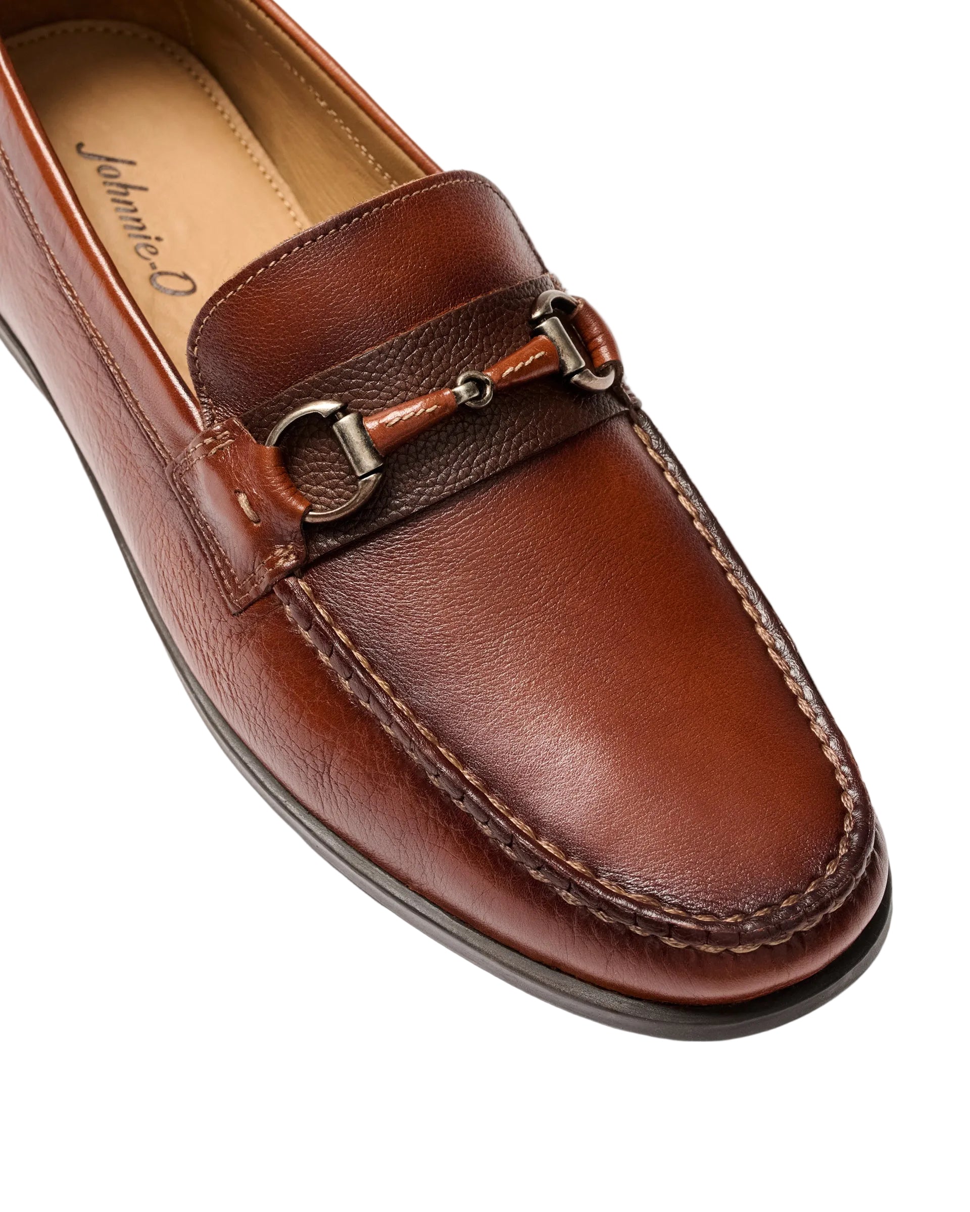 Brown leather loafer with a decorative buckle on a light gray background