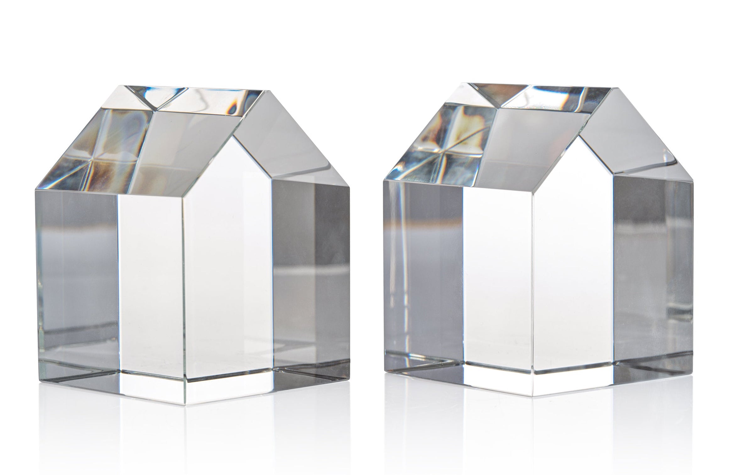 Two clear glass or acrylic house-shaped decorative objects on a clean white background.
