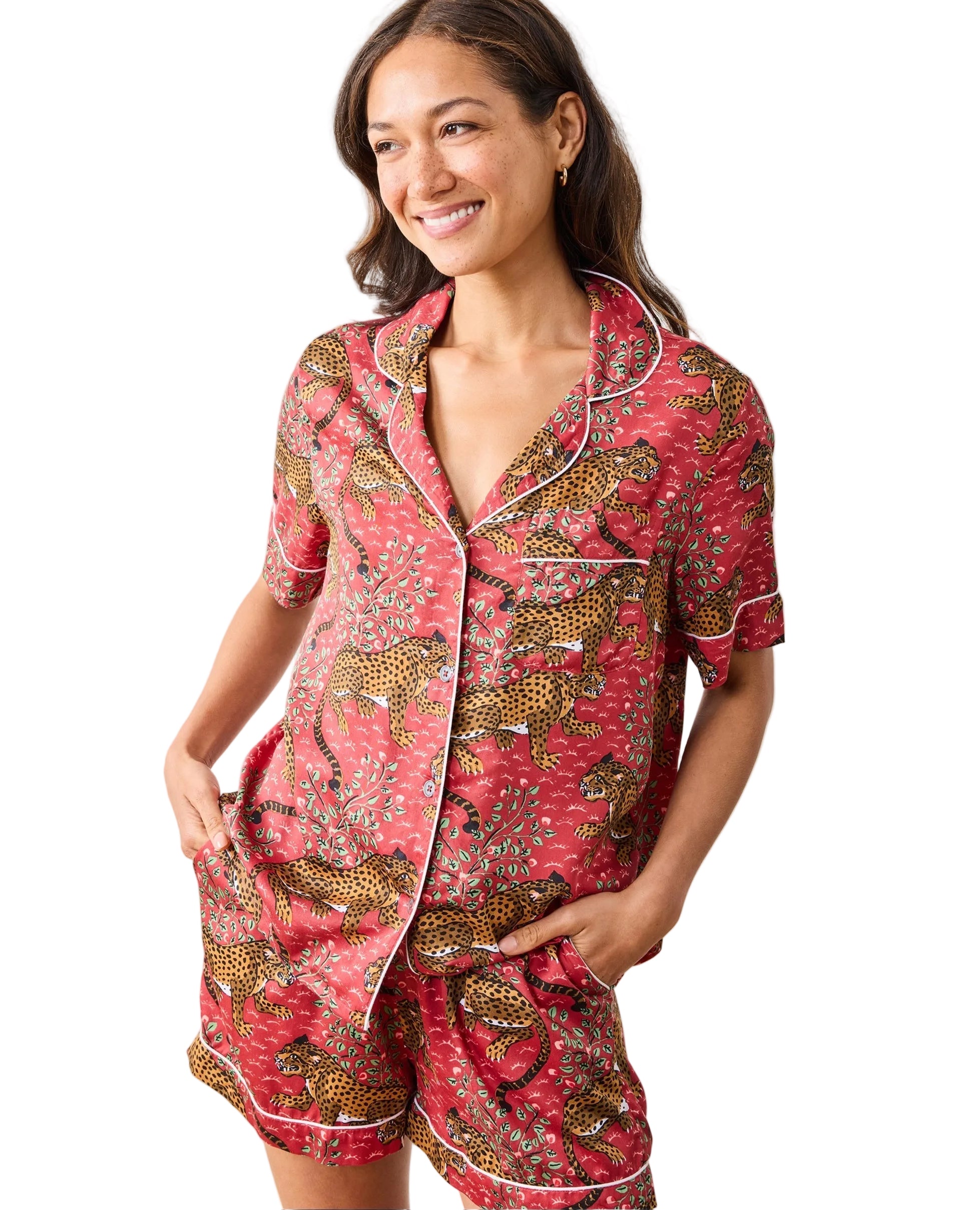 Woman wearing a red pajama set with animal print on a plain background