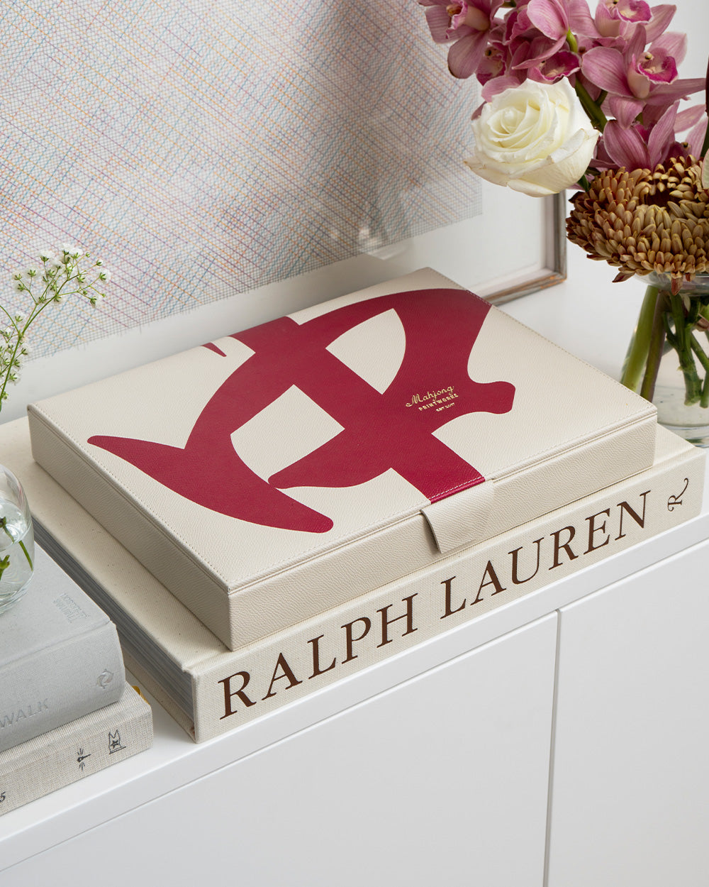 Ralph Lauren box with a red logo on top of books, surrounded by flowers.