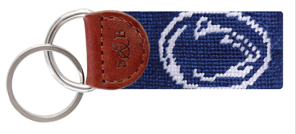Keychain with navy strap featuring a white logo and brown leather accent on a white background
