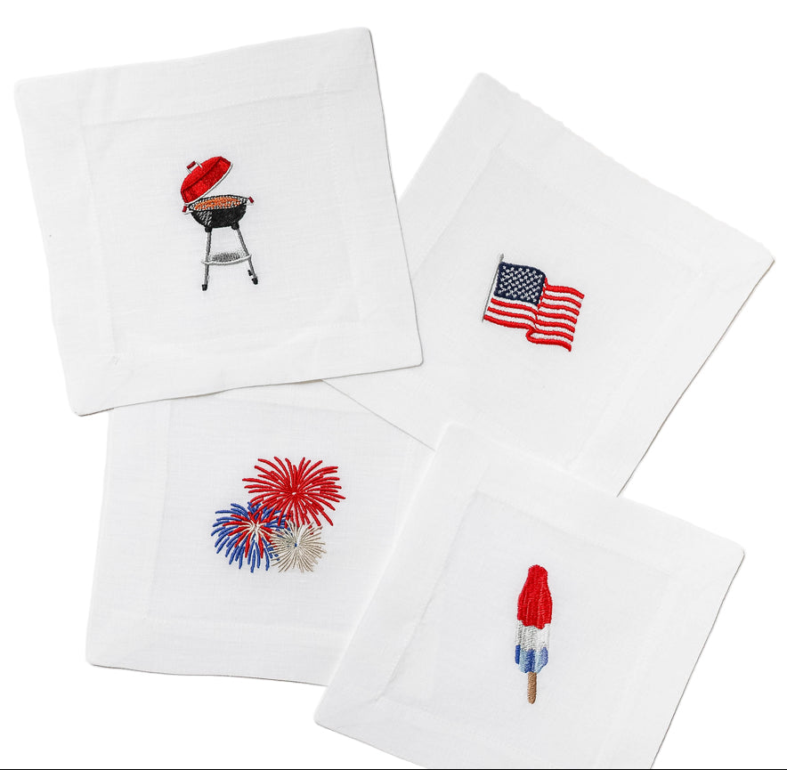 Four white napkins with embroidered designs on a white background