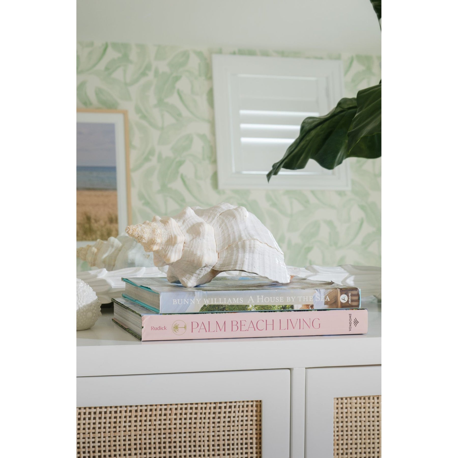Decorative setup with books and a shell on a surface against a patterned wall.