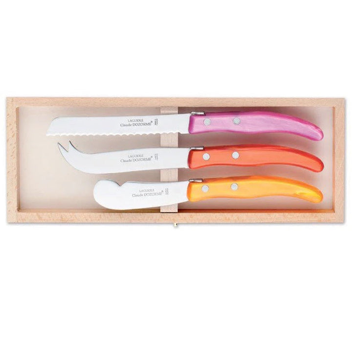 Set of three cheese knives with colorful handles in a wooden box on a white background