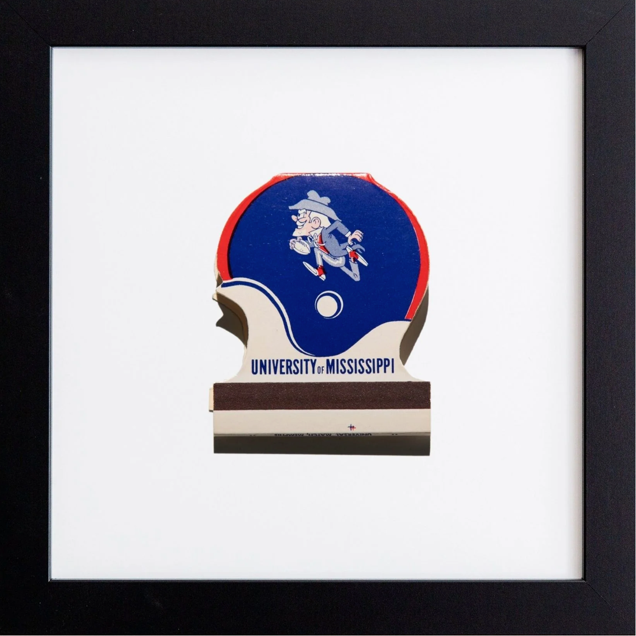 Framed artwork of a blue and red logo with a cartoon character, featuring 'University of Mississippi' text.