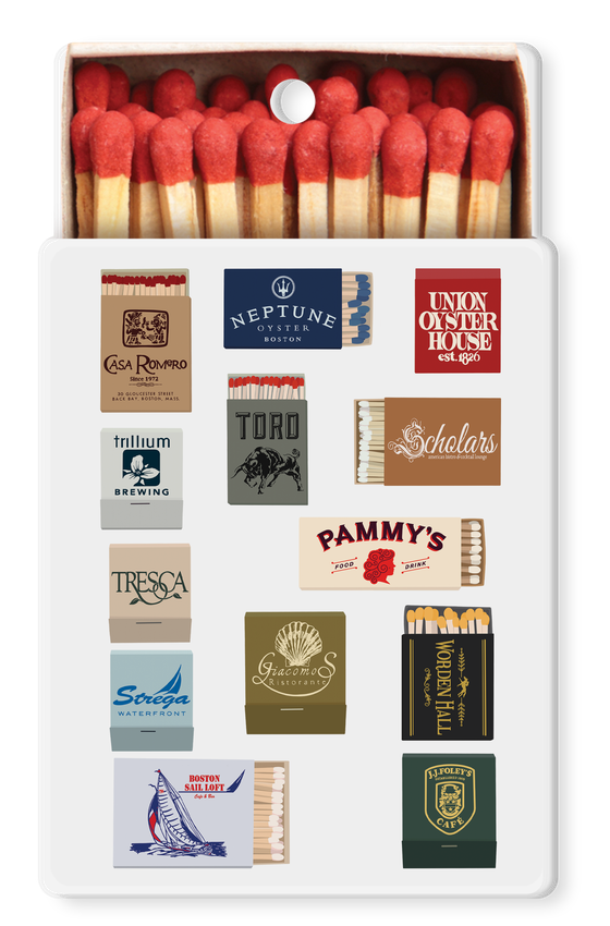 A white rectangular matchbox with red match heads visible at the top and a grid of vintage-style match label designs on the front, shown against a plain white background.