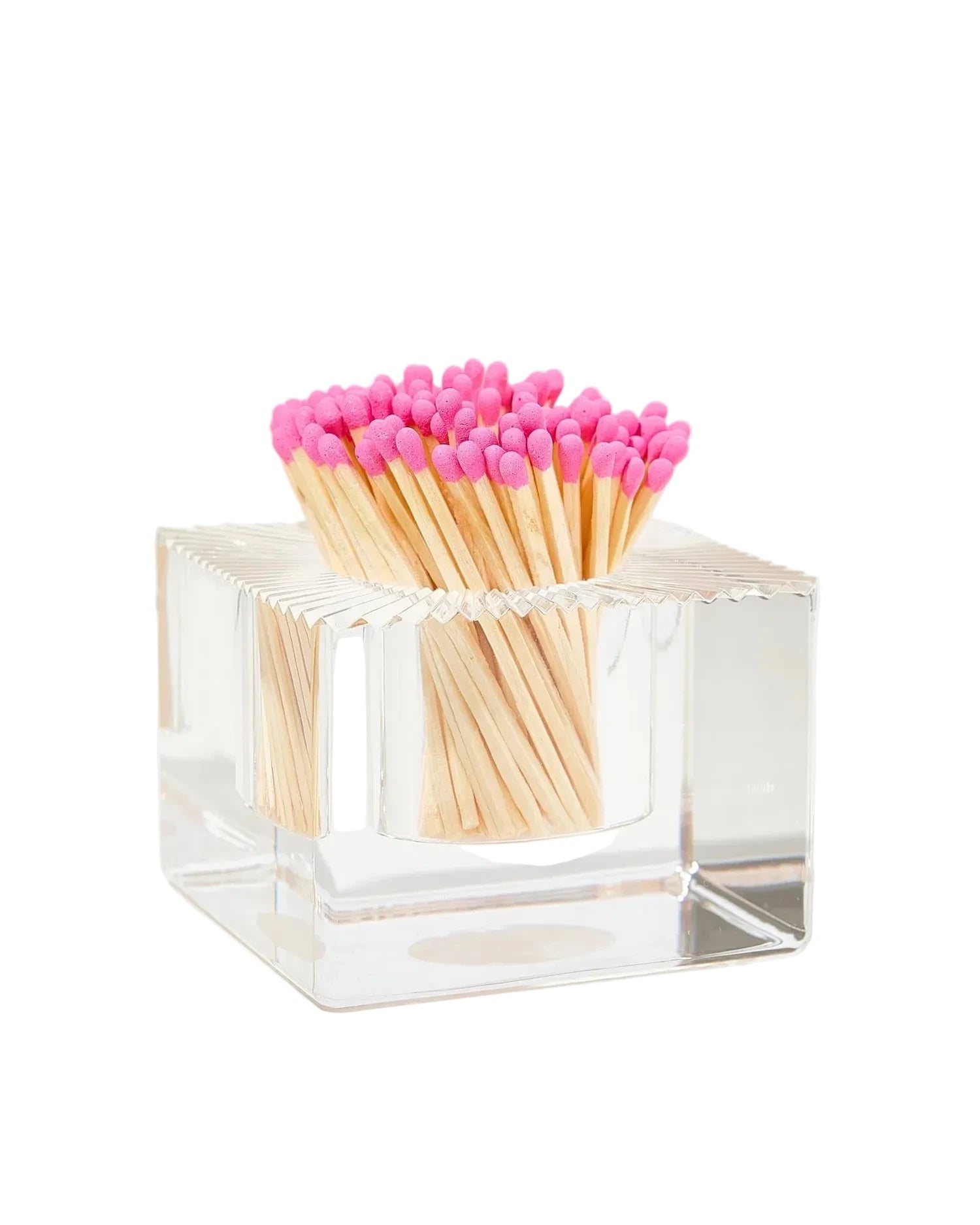 Clear cube-shaped matchbox with pink matches on a white background