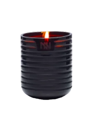 Black ribbed candle holder with a lit candle on a light gray background