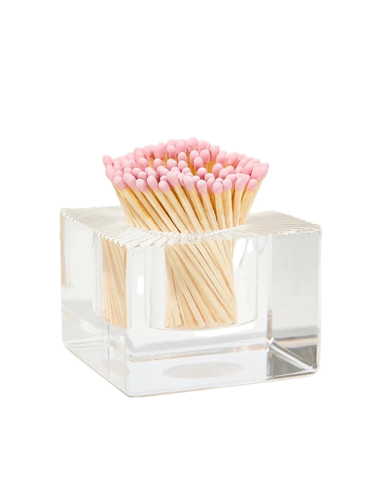 Clear cube-shaped matchbox with pink and beige matches on a white background