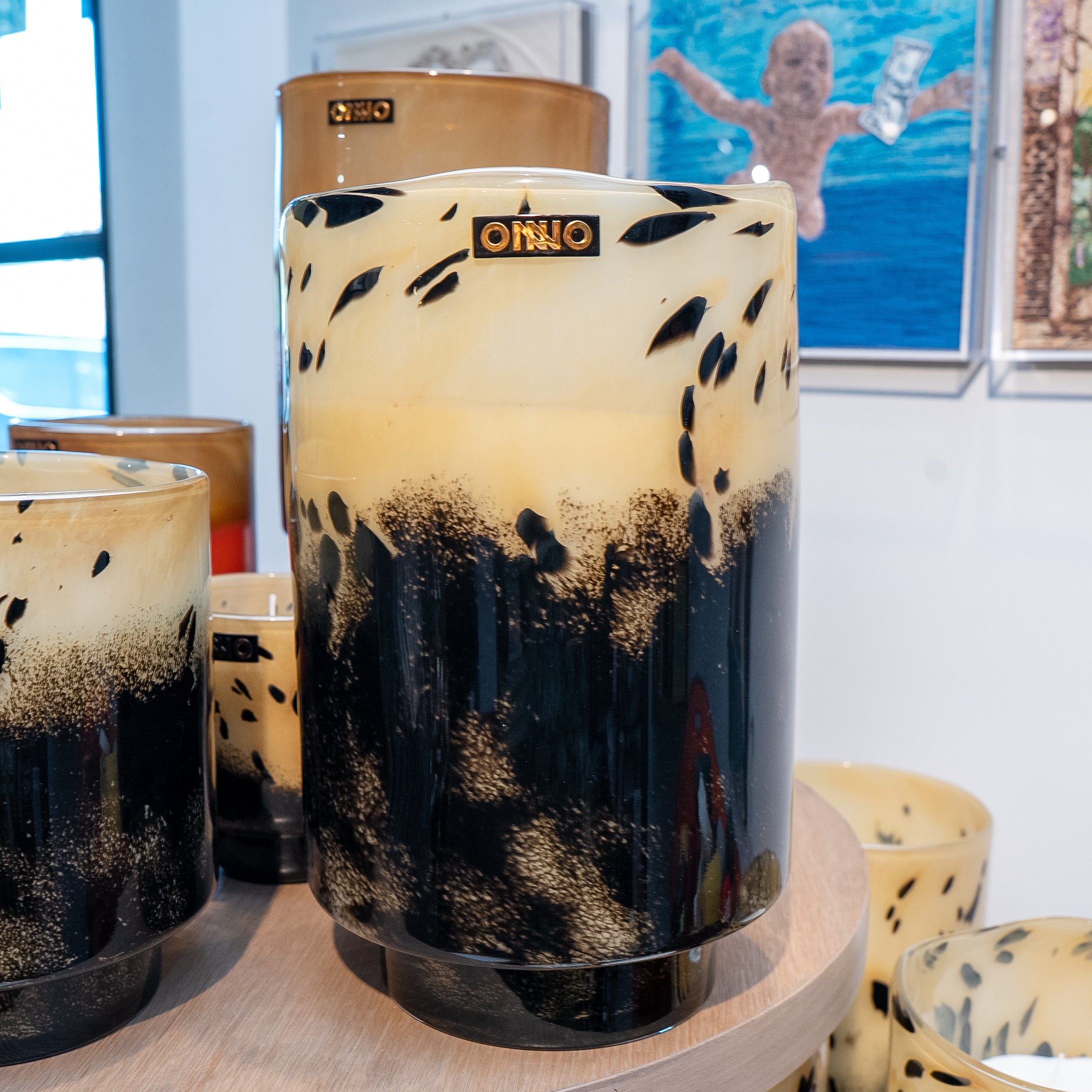 Decorative cylindrical vase with black speckles on a wooden surface, with 'Onno' branding.