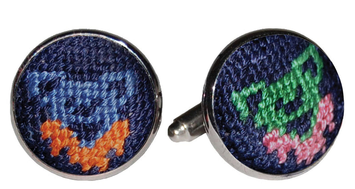 A pair of round silver cufflinks with colorful embroidered faces on a white background. One cufflink features a blue and orange fox, and the other features a green cat and pink mouse.