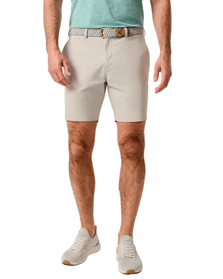 Person wearing light gray shorts and a turquoise shirt on a beige background