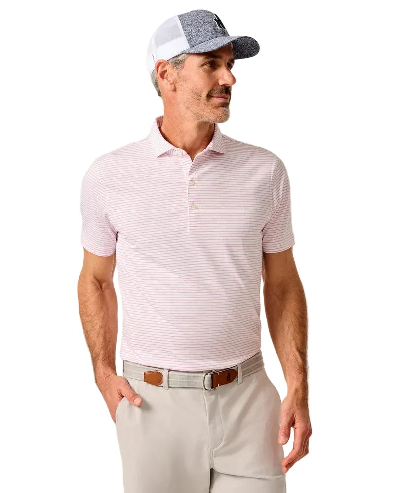 Man wearing a pink striped polo shirt and beige pants against a neutral background