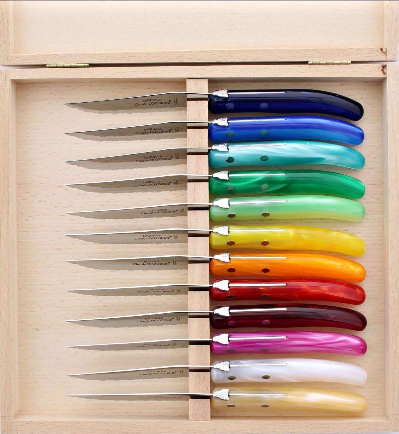 Set of colorful knives in a wooden box on a white background