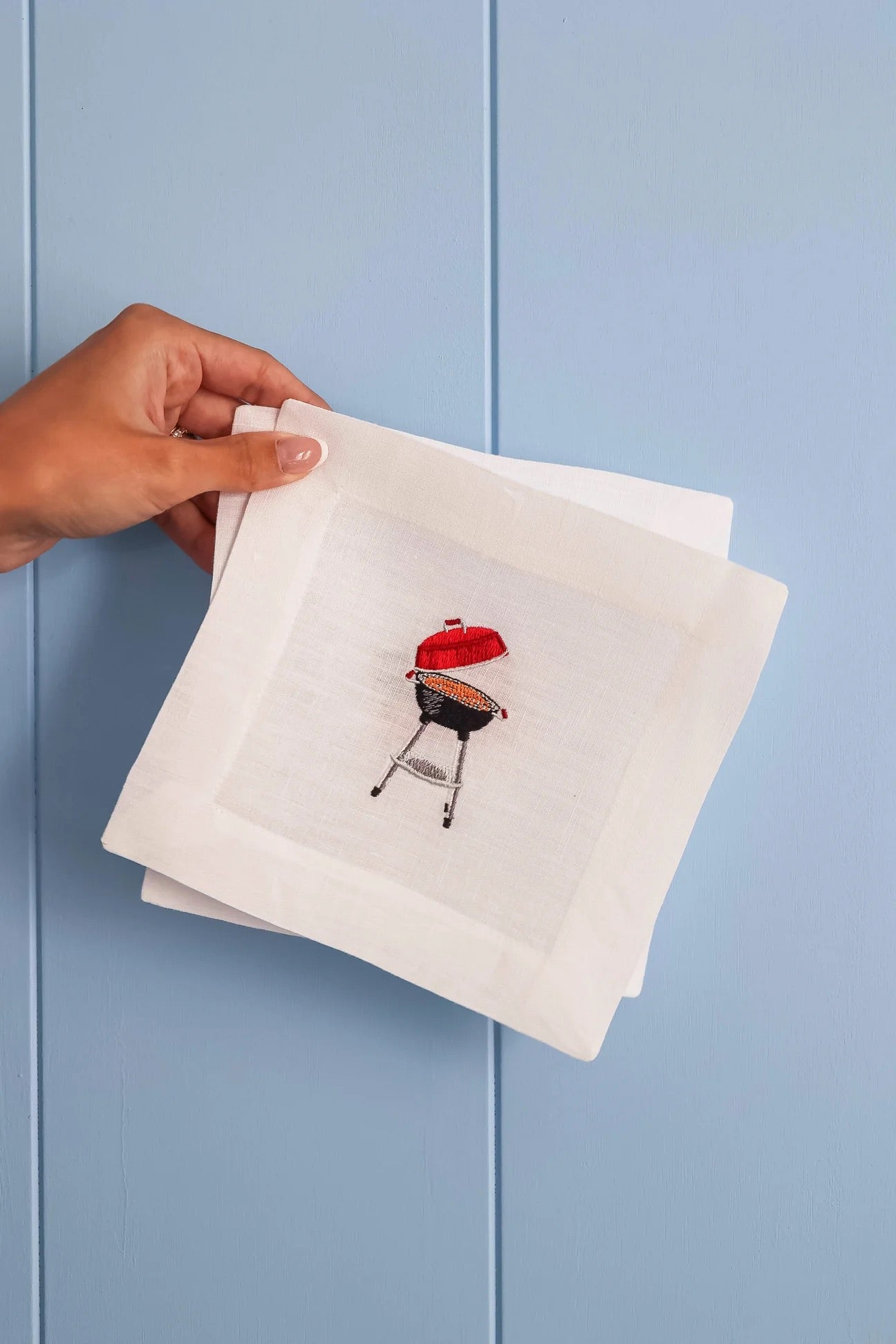 Napkin with a grill design held by a hand against a light blue background
