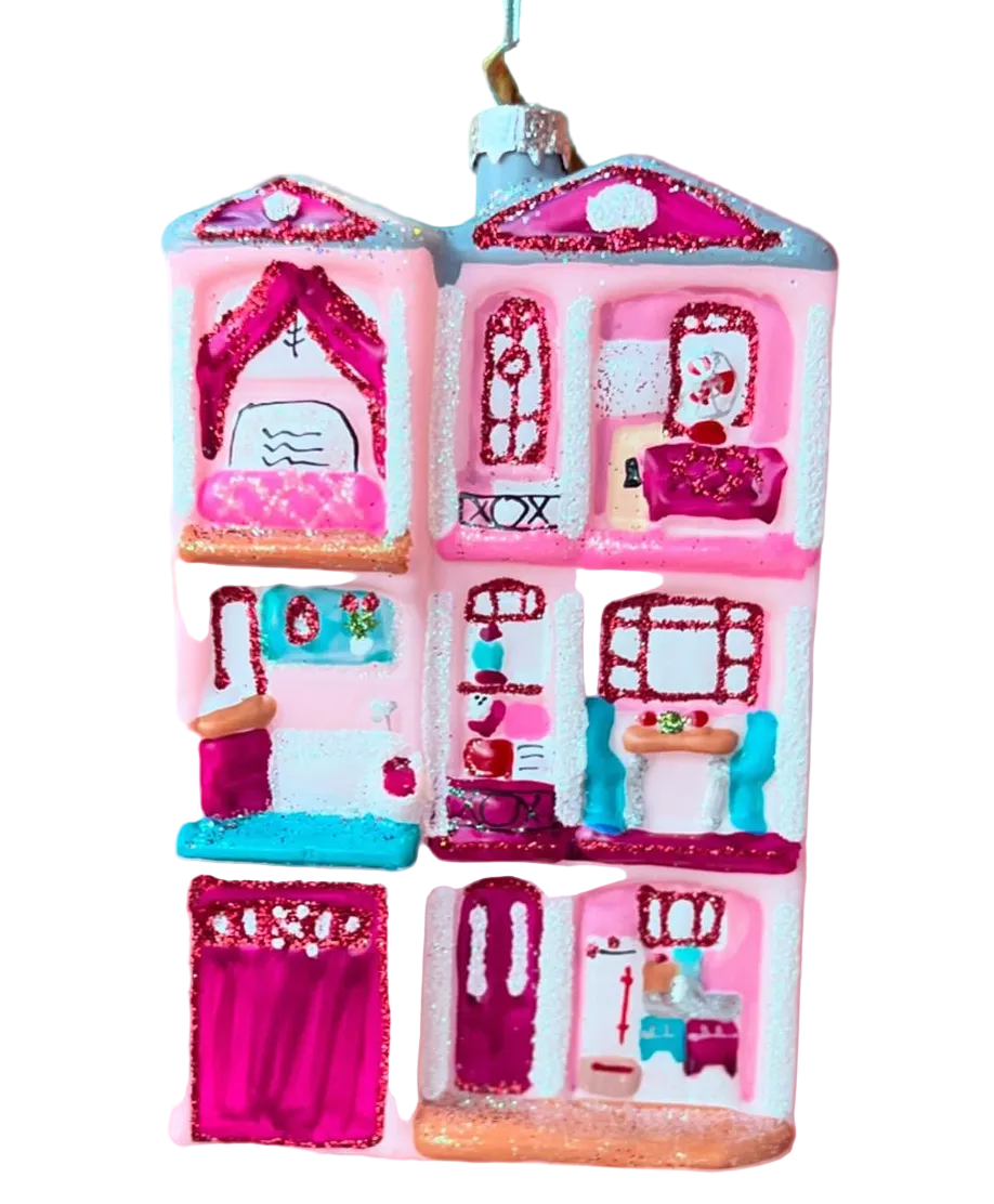 Decorative ornament shaped like a pink dollhouse with detailed rooms on a colorful background