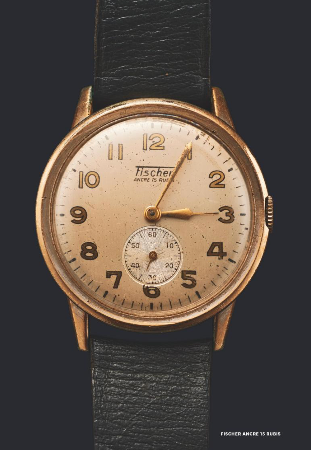 Vintage wristwatch Fischer Ancre 15 Rubis with a black leather strap on a dark background