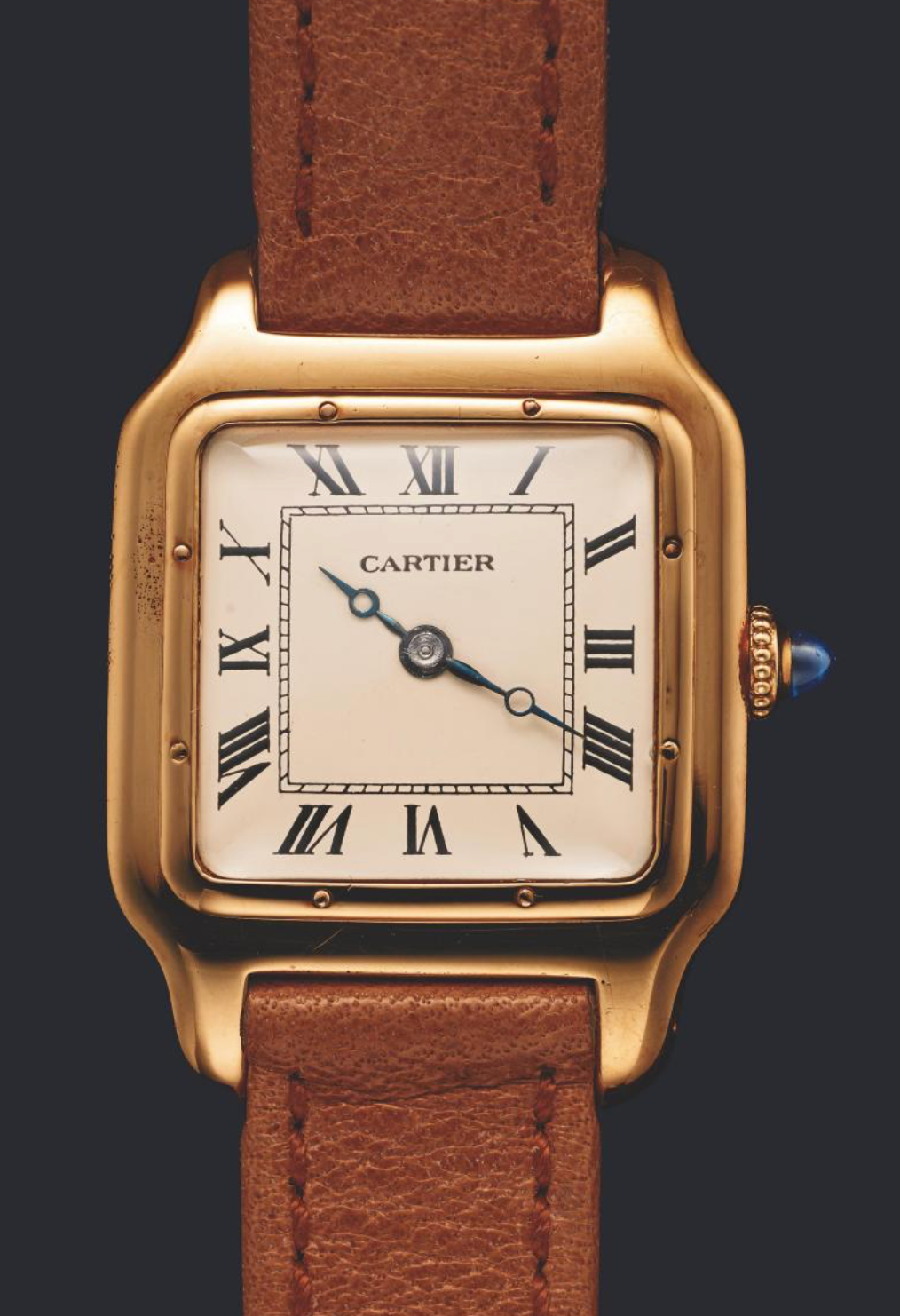 Cartier watch with gold case and brown leather strap on a dark background