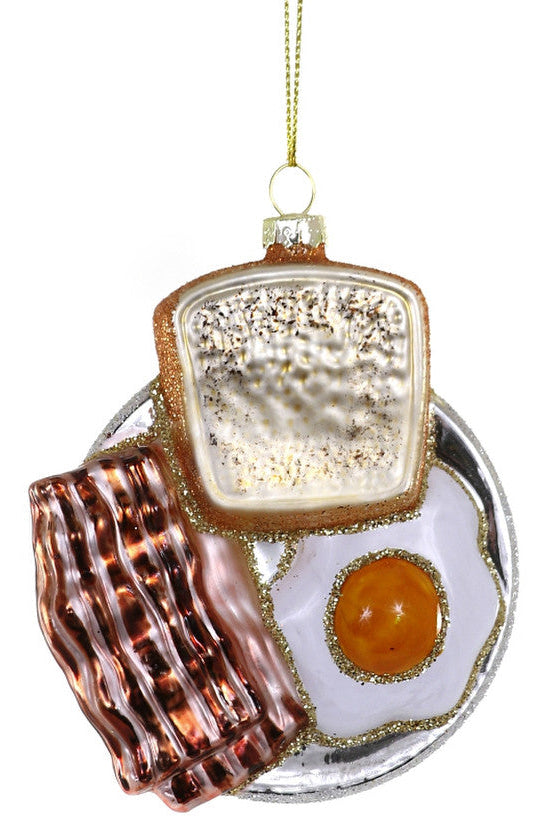 A glass ornament designed to look like a breakfast meal, including a sandwich, eggs, and bacon, with a glossy finish and a gold-colored chain for hanging.