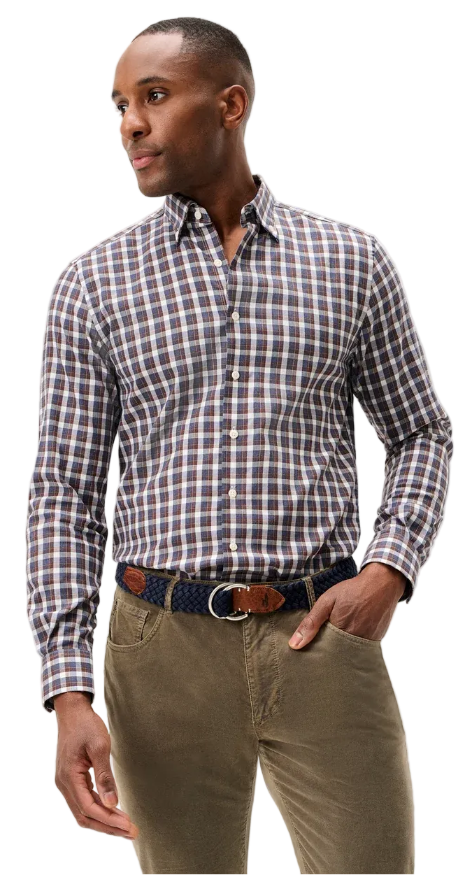 A man wearing a long-sleeve button-down shirt with a brown, white, and blue checkered pattern, paired with olive green trousers and a patterned belt, photographed against a light gray studio background.