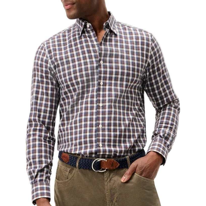 A man wearing a long-sleeve button-down shirt with a brown, white, and blue checkered pattern, paired with olive green trousers and a patterned belt, photographed against a light gray studio background.