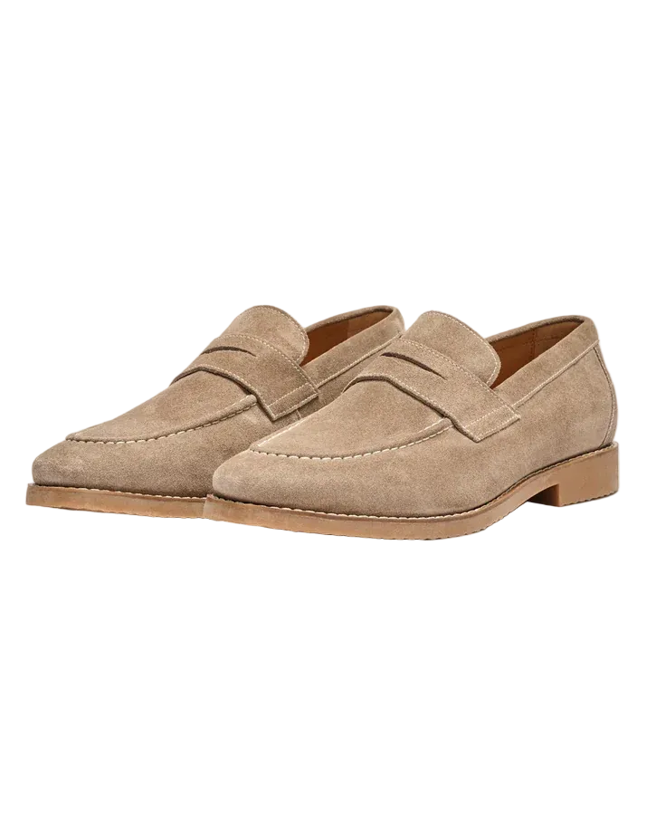 Pair of beige loafers on a light beige background