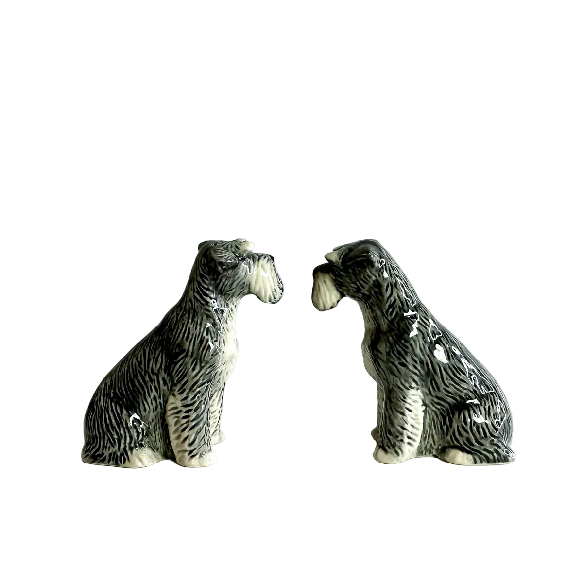 Two ceramic dog figurines facing each other on a plain background