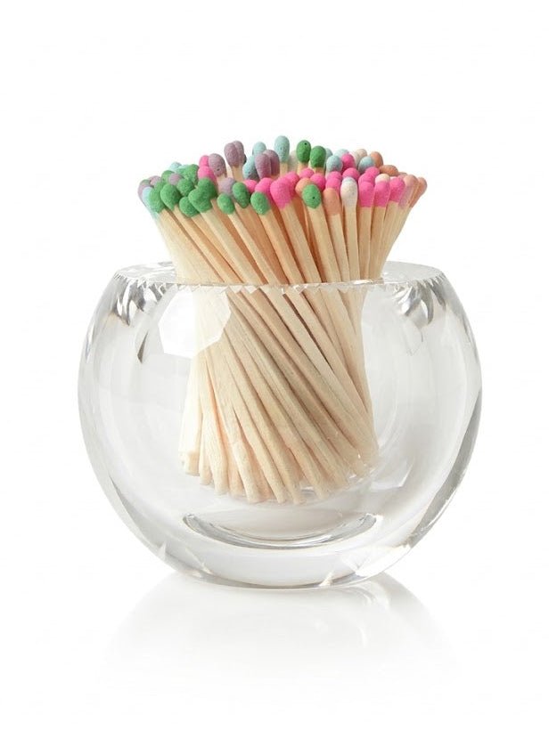 Clear glass match holder with colorful matches on a white background