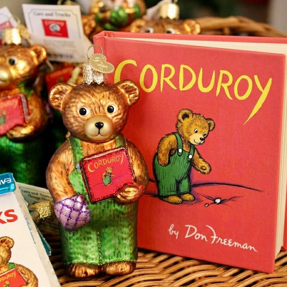 Decorative bear ornament holding a 'Corduroy' book with the book in the background.
