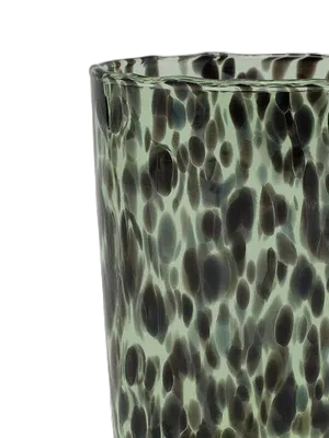 Green glass vase with a spotted pattern on a light gray background