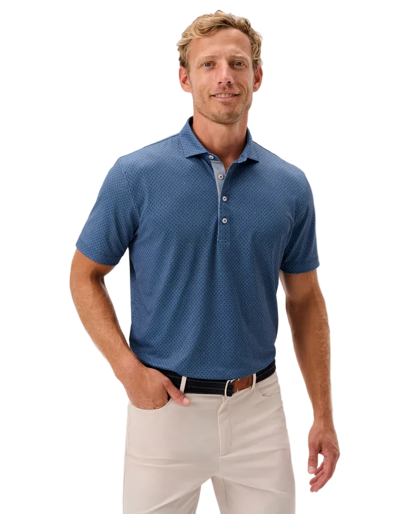 Man wearing a blue patterned polo shirt and beige pants on a light gray background