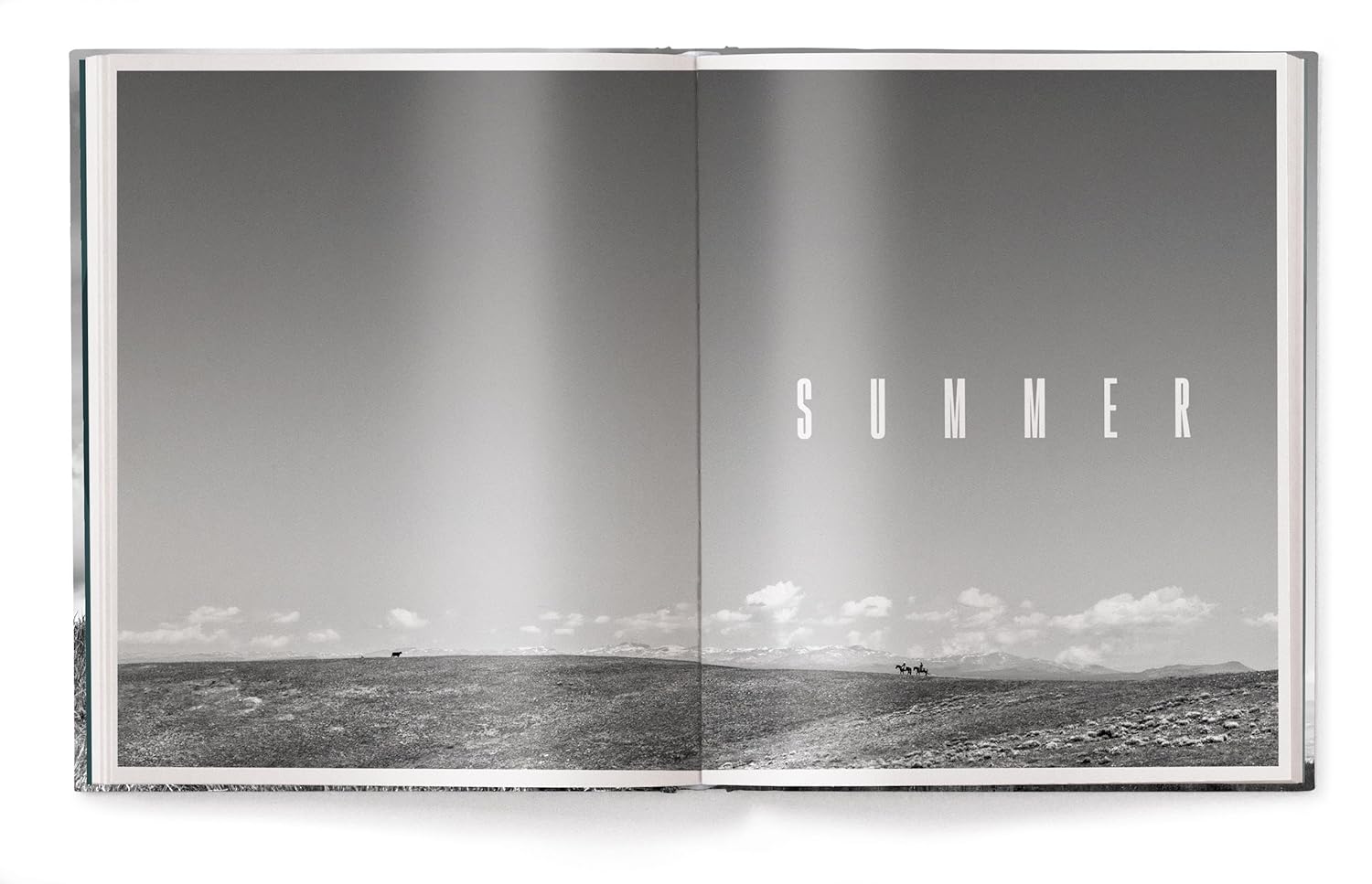 Book open to a page with a black and white photograph of a beach and the word 'SUMMER' in white text.