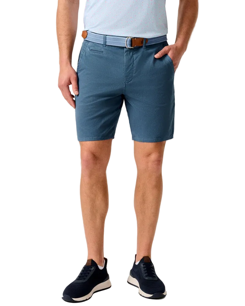 Person wearing blue shorts and navy shoes on a beige background