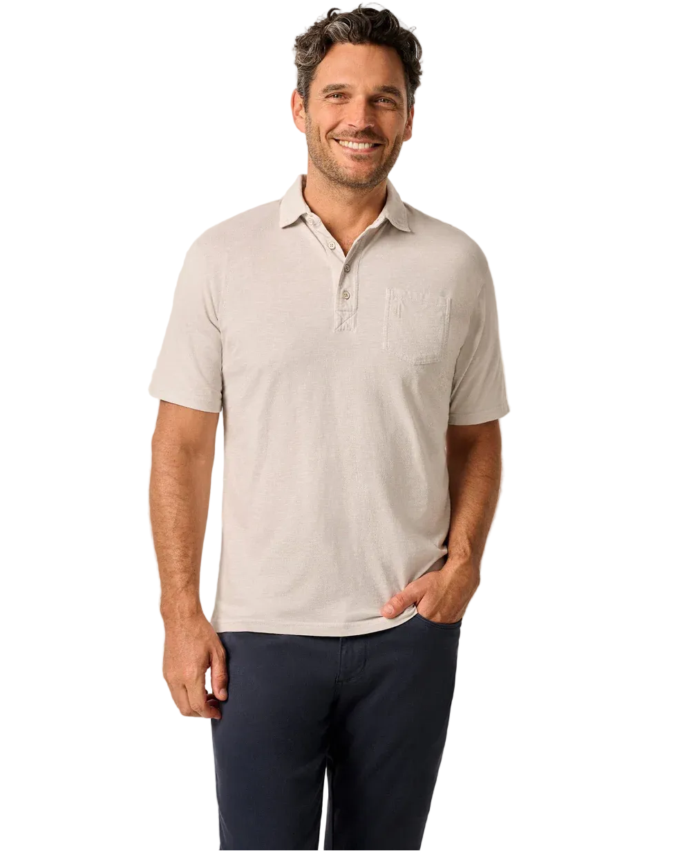 Man wearing a light gray polo shirt with a logo on a beige background
