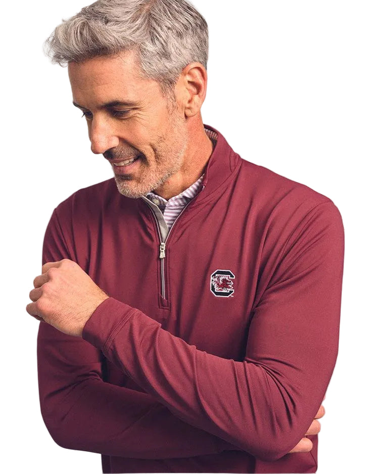 Man wearing a maroon pullover with a logo on a light gray background