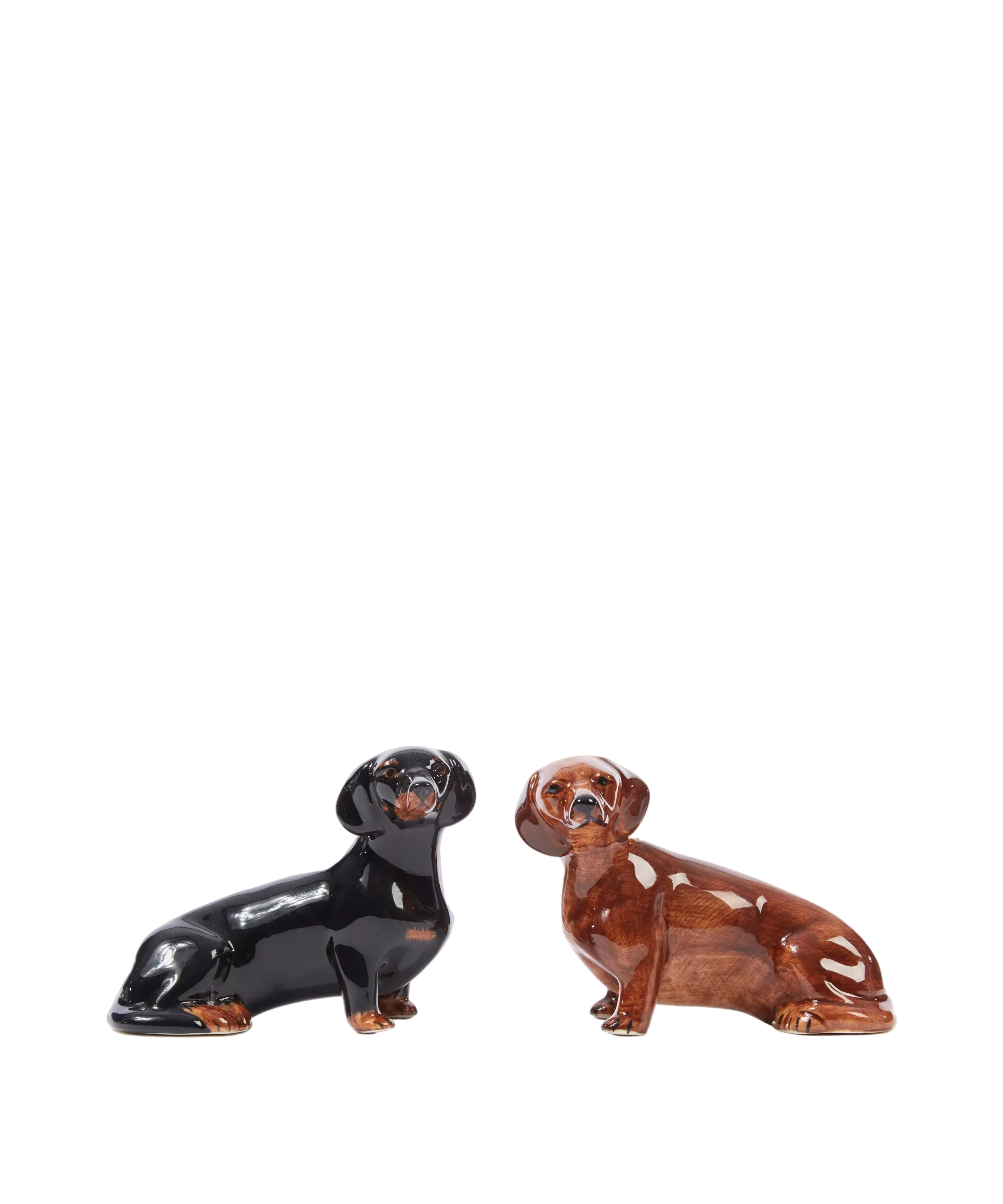 Two ceramic dog figurines, one black and one brown, on a white background