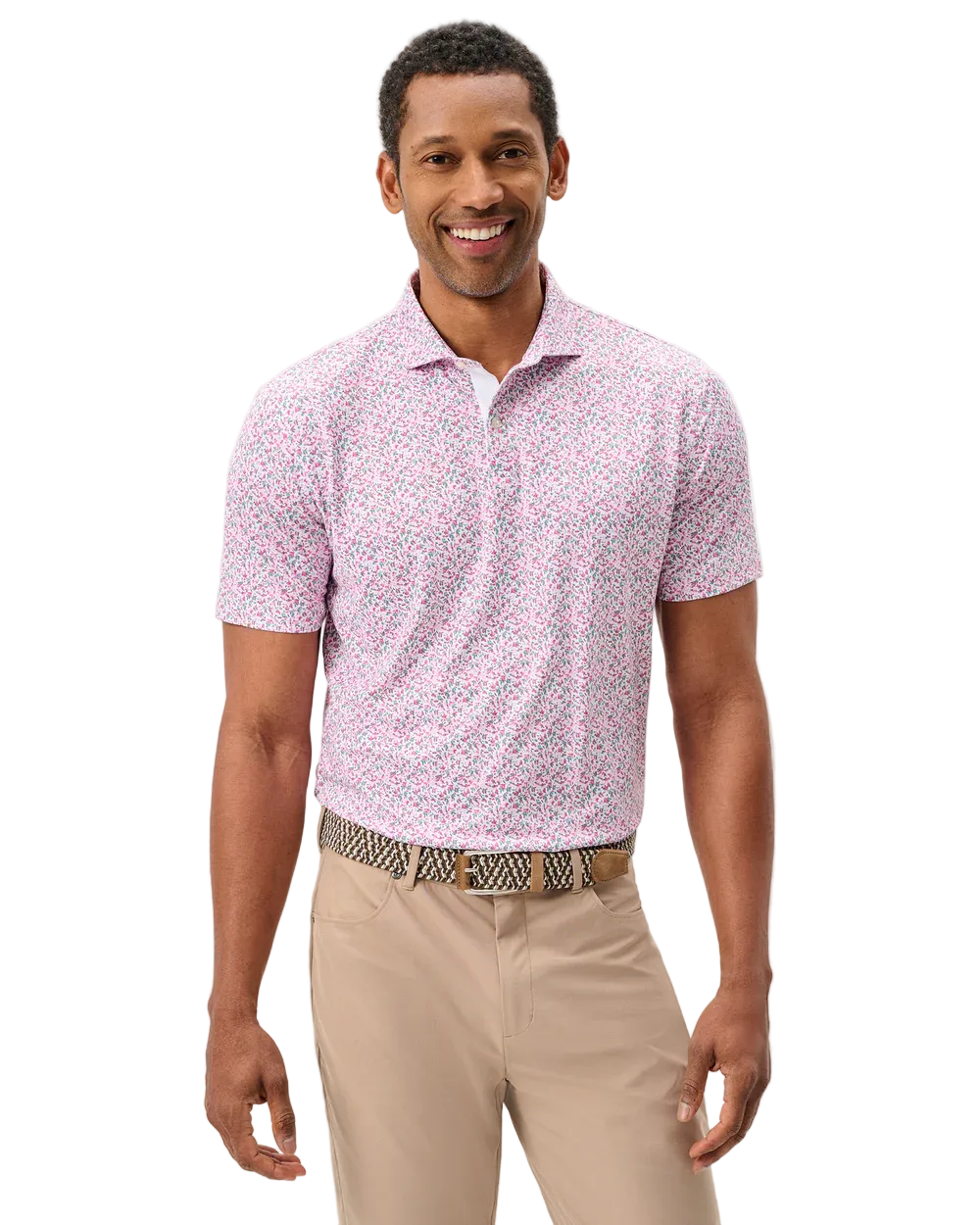 Man wearing a pink patterned polo shirt and beige pants on a light gray background