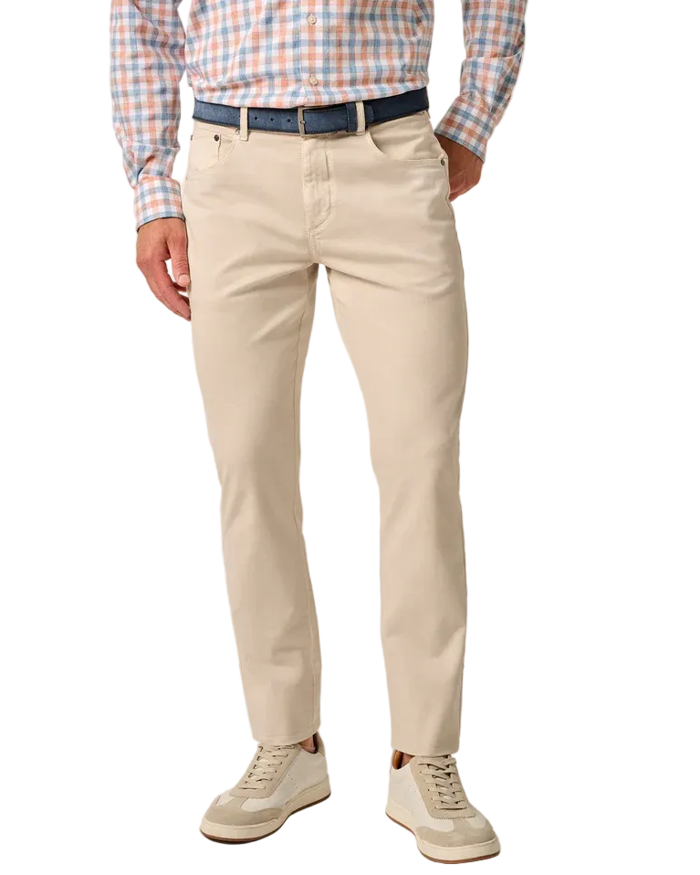 Person wearing a checkered shirt, beige pants, and white sneakers on a plain background