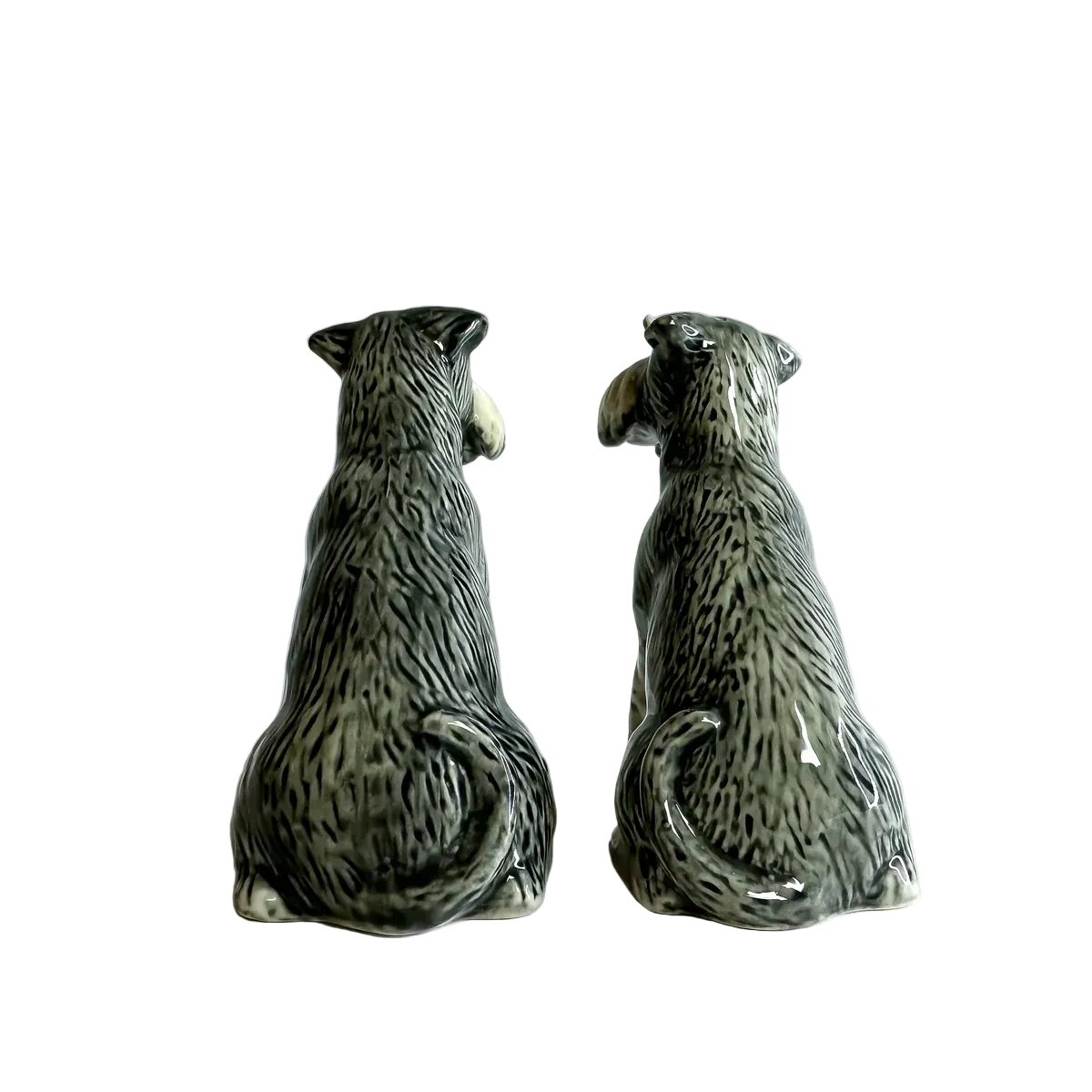 Two ceramic dog figurines sitting side by side on a white surface with a light gray background.