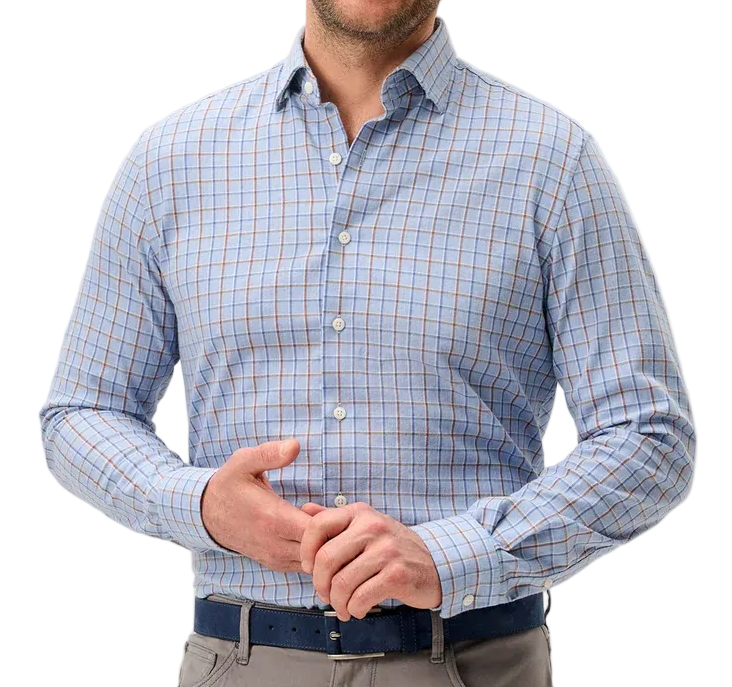 A smiling man wearing a light blue and white checkered long-sleeve button-down shirt, gray trousers, and a dark blue belt, standing against a light gray studio background.