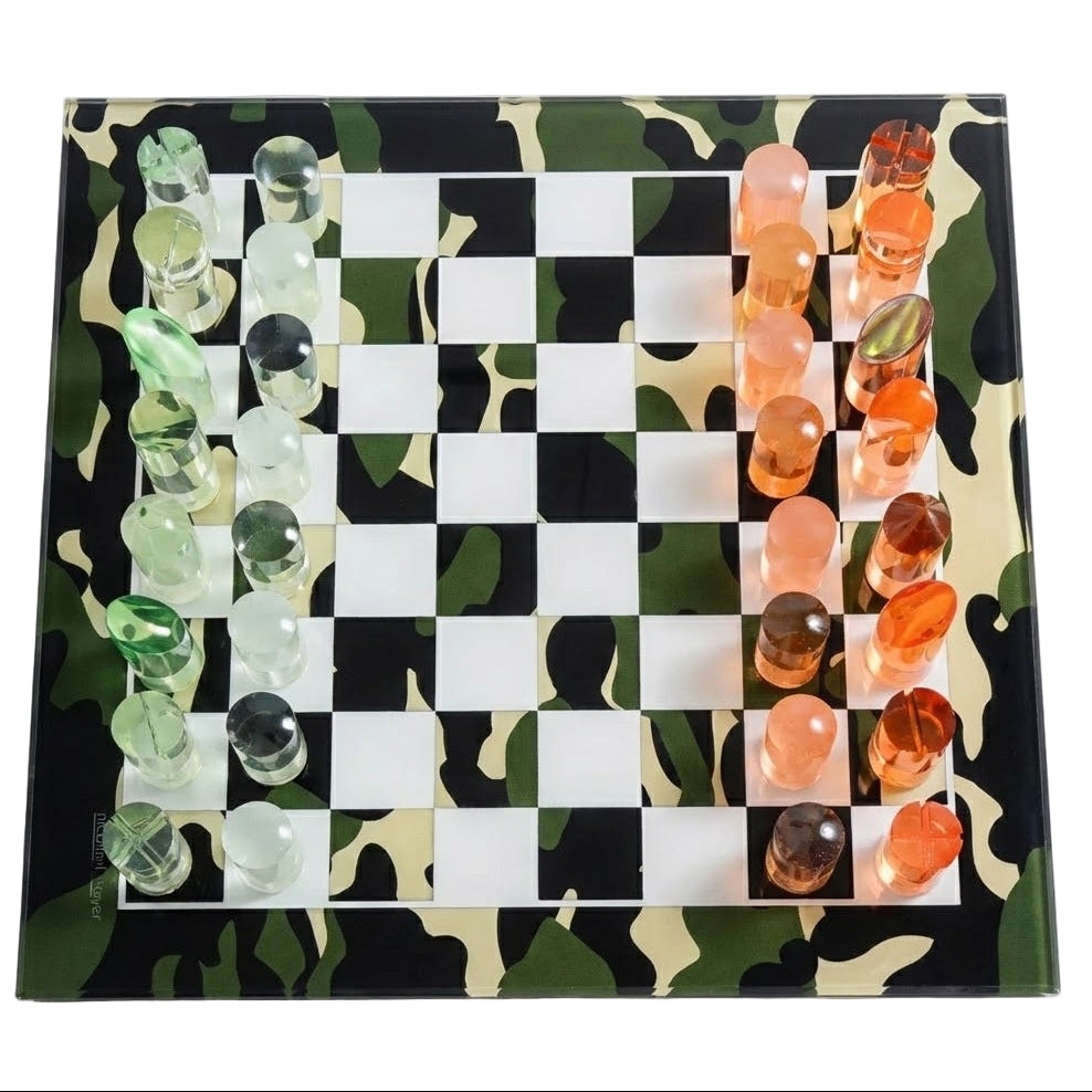 Chess game set with green and orange pieces on a camouflage-patterned board