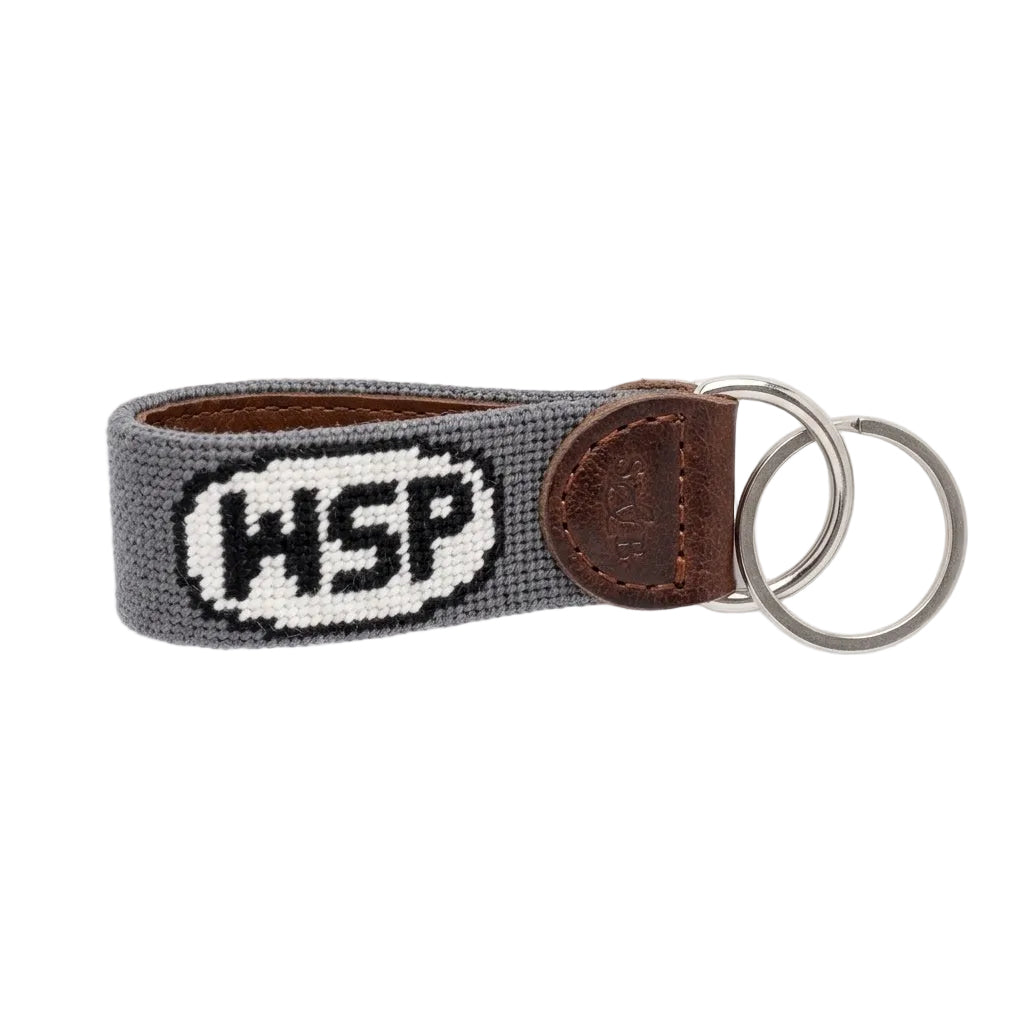 Keychain with 'HSP' logo on a gray strap with brown leather accent on a white background